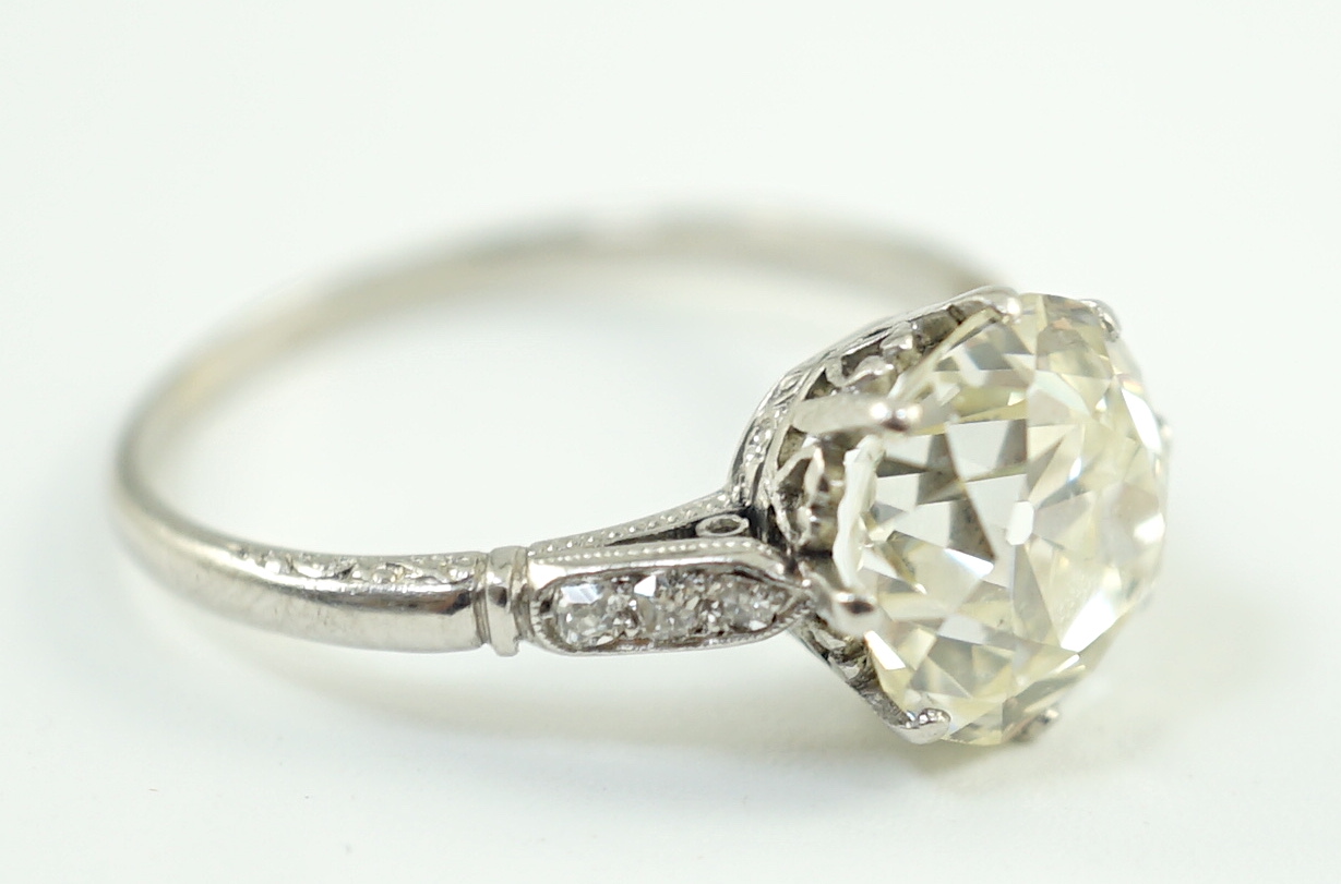 A mid 20th century platinum and single stone diamond ring, with six stone diamond chip set shoulders